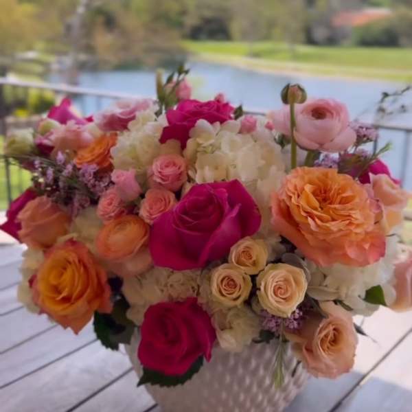 Mixed bouquet of pink, peach, and white roses in a white vase