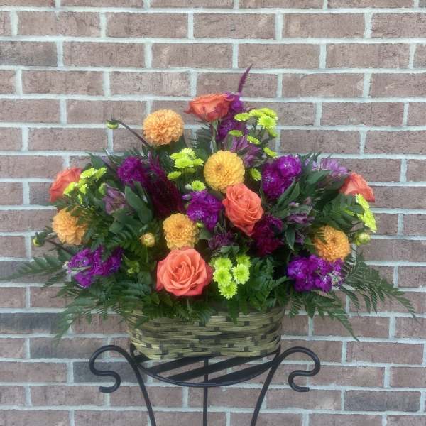 Basket of orange roses and purple flowers on a stand