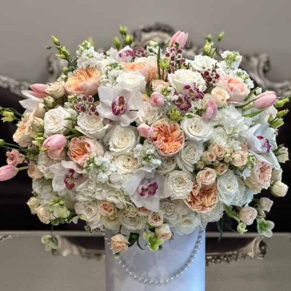 Large pastel bouquet of roses, tulips, and orchids in a white hatbox