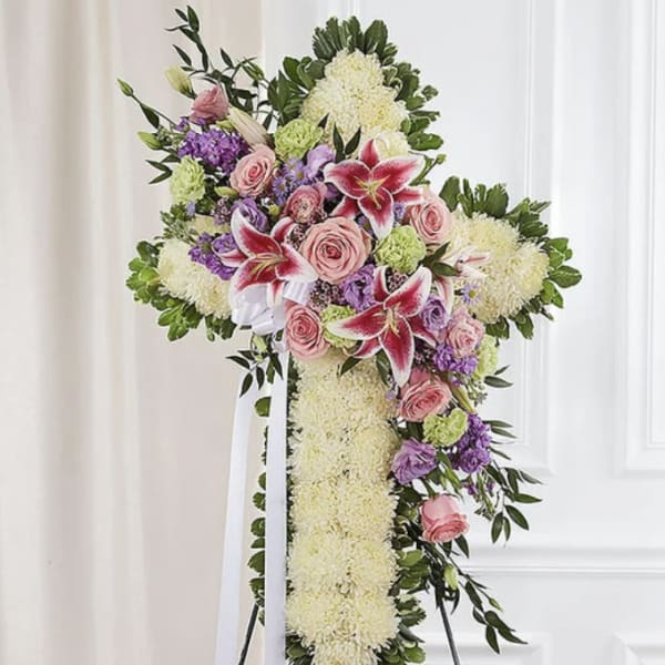 Standing floral cross with pink roses and lilies on a white easel