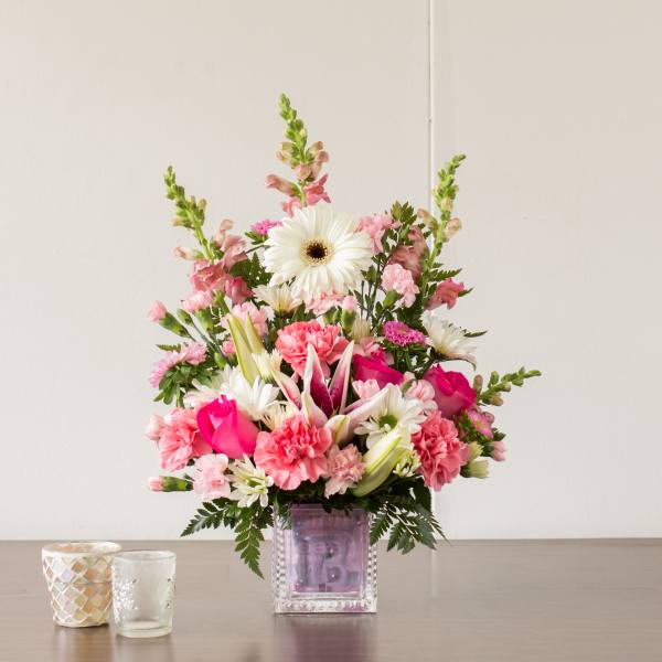 Pink and white mixed flower arrangement in a square glass vase