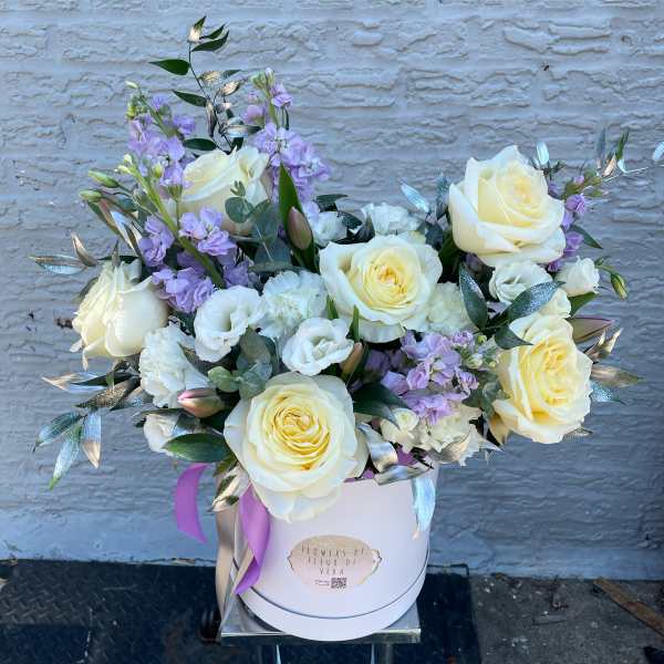 Cream roses and lavender flowers in a white hat box