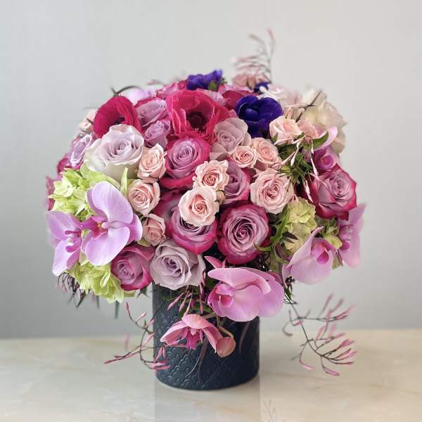 Pink and purple roses with orchids in a dark vase