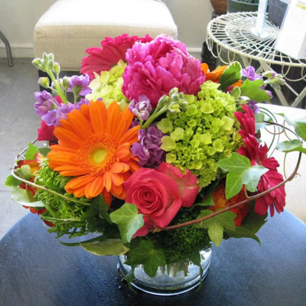 Colorful bouquet with gerbera daisies, roses, and hydrangeas in a glass vase