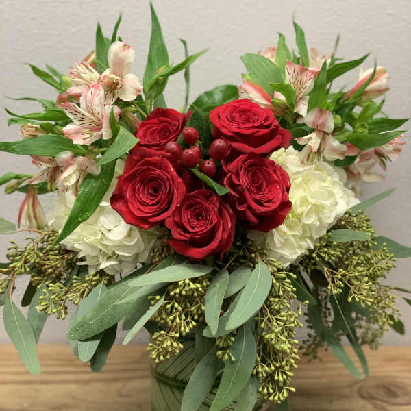 Red roses and white blooms arranged in a glass vase