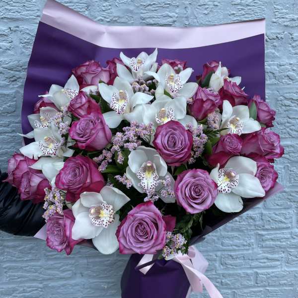 Bouquet of pink roses and white orchids wrapped in purple paper