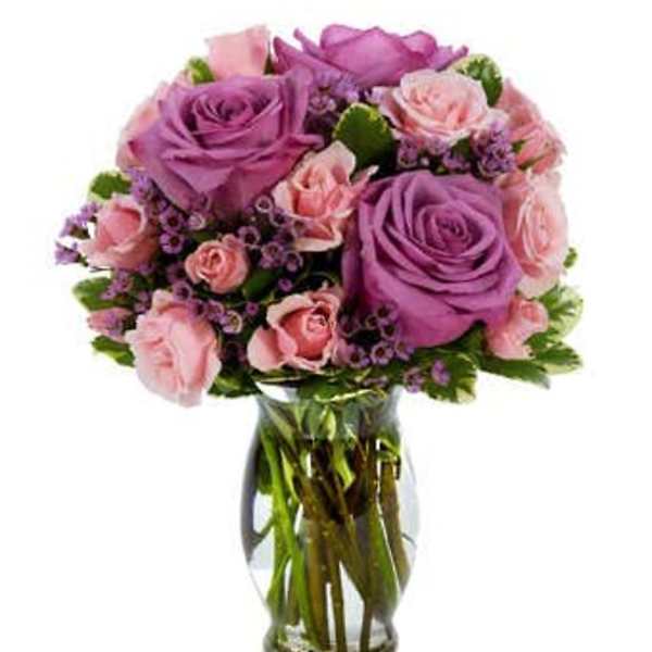 Bouquet of purple and pink roses in a clear glass vase