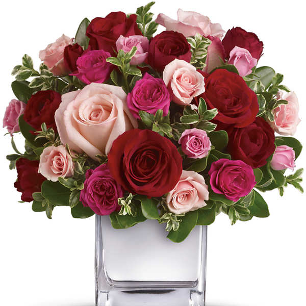 Bouquet of red, pink, and blush roses in a clear glass vase
