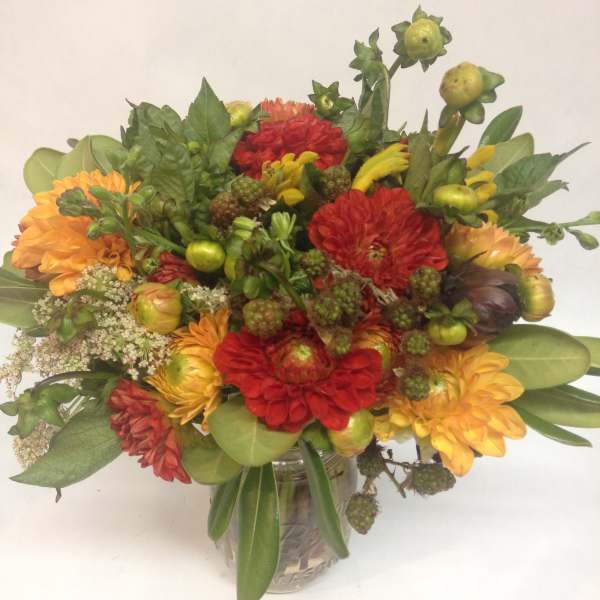 Mixed bouquet of red and orange flowers in a glass vase