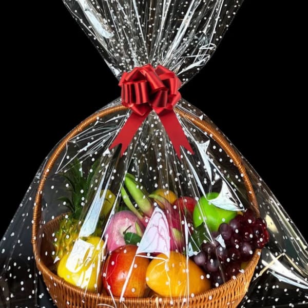 Gift basket of assorted fruit wrapped in clear cellophane with a red bow