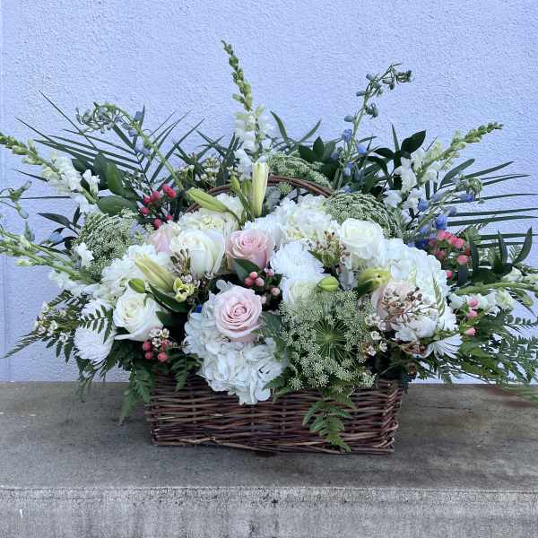 Large basket arrangement of white and pale pink flowers with tall accents