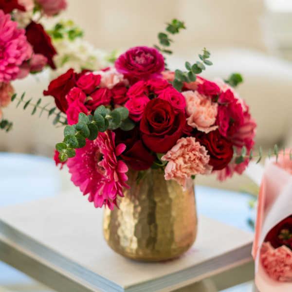 Pink and red flower bouquet in a gold vase
