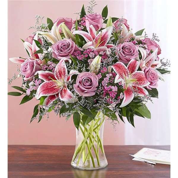 Pink roses and stargazer lilies arranged in a clear glass vase