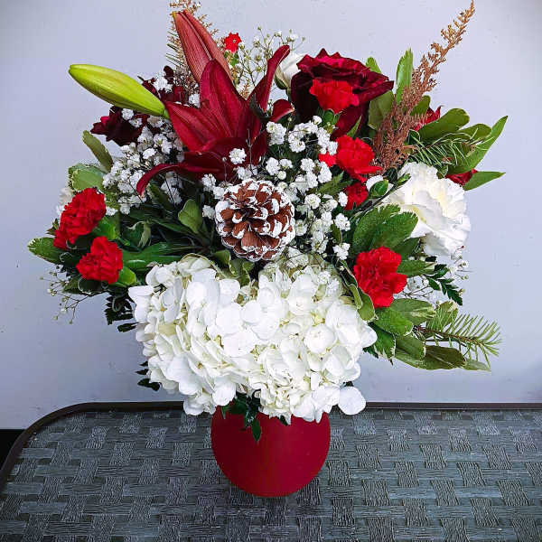 Red and white floral arrangement in a red vase