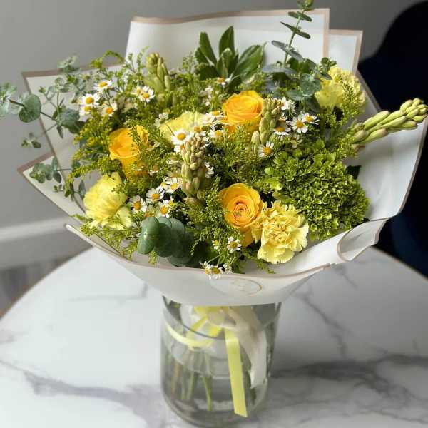 Yellow roses and small white daisies in a glass vase