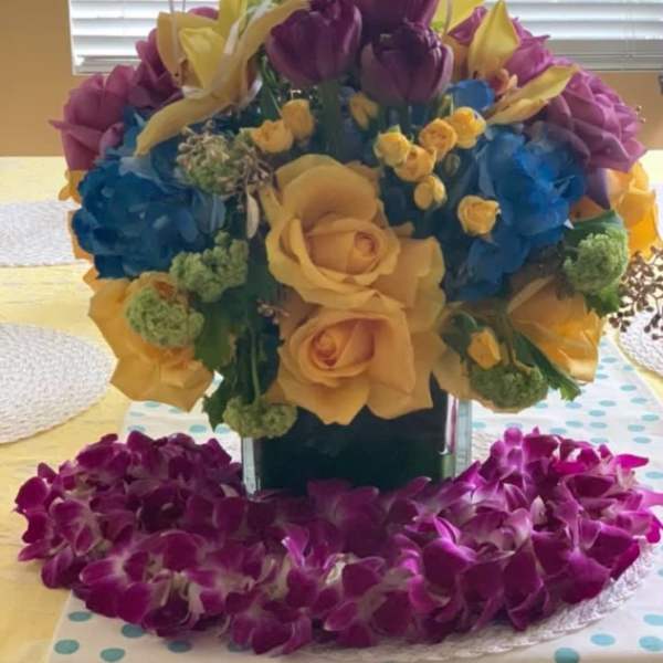 Bouquet of yellow roses, purple tulips, and blue hydrangeas in a vase