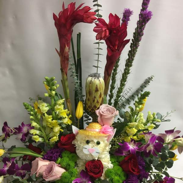 Colorful floral arrangement with a cat face centerpiece and orchids