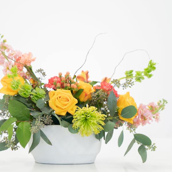 Yellow roses and mixed flowers in a white container
