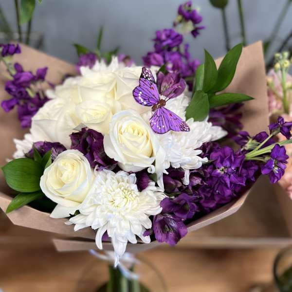 Bouquet of white roses and purple flowers with a butterfly decoration