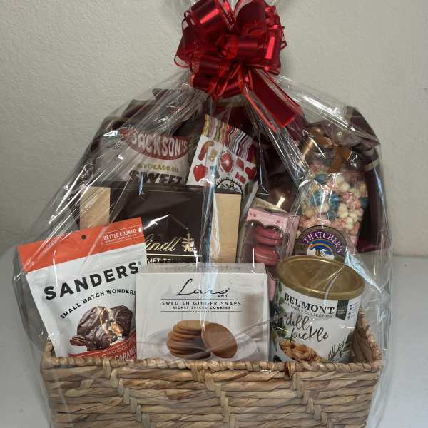 Gift basket of assorted snacks and sweets wrapped in clear cellophane with a red bow