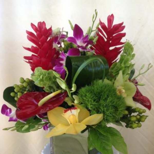 Tropical bouquet with red, purple, and yellow orchids in a glass vase