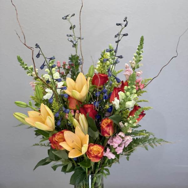 Mixed bouquet of lilies, roses, and snapdragons in a glass vase