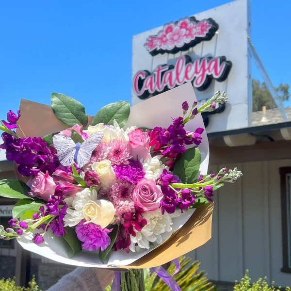 Bouquet of pink, white, and purple flowers with a butterfly decoration