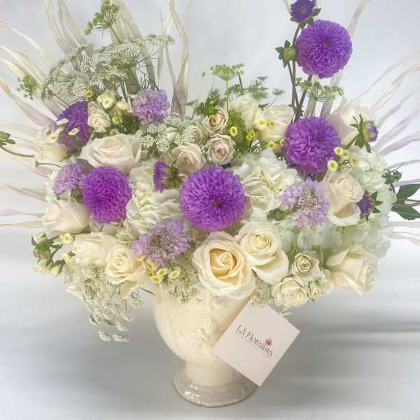 Cream and purple floral arrangement in a glass vase