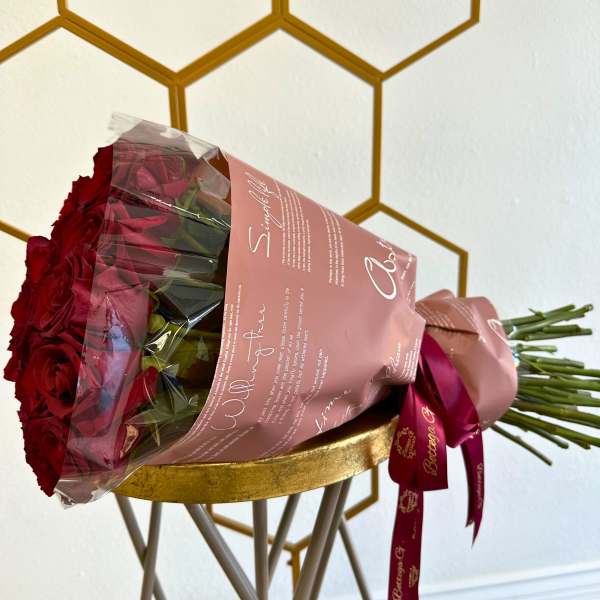 Bouquet of red roses wrapped in pink paper with a ribbon