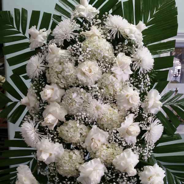 White floral standing spray with large palm leaves