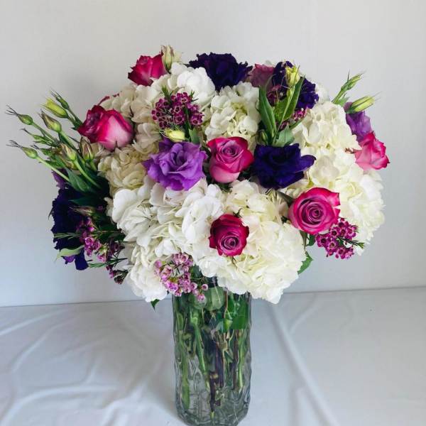 Bouquet of white hydrangeas and pink and purple roses in a glass vase