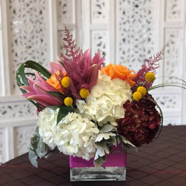 Mixed bouquet with hydrangeas, roses, and lilies in a square glass vase