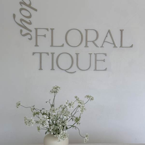 White wildflower arrangement in a cream vase beneath wall lettering