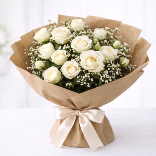 Bouquet of white roses wrapped in brown paper with a satin ribbon