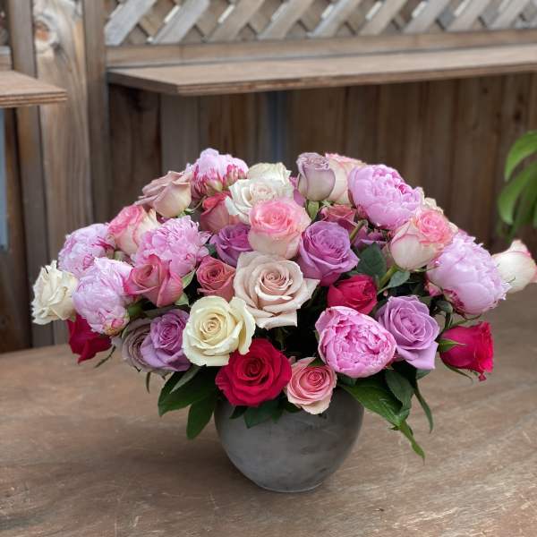 Mixed pink and white roses arranged in a gray vase