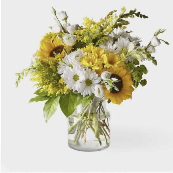 Yellow sunflowers and white daisies in a clear glass vase