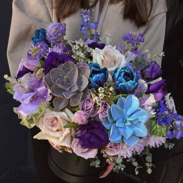 Large bouquet of purple, blue, and white flowers in a black box