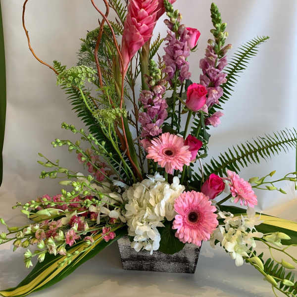 Tall pink floral arrangement in a rectangular vase with gerberas and orchids