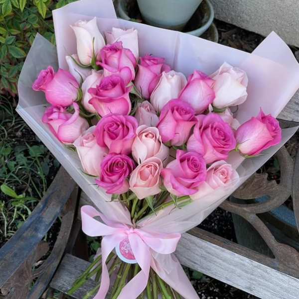 Bouquet of pink and pale pink roses wrapped in light paper with a ribbon