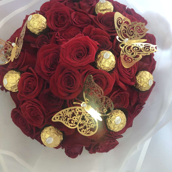 Bouquet of red roses with gold-wrapped chocolates and butterfly decorations