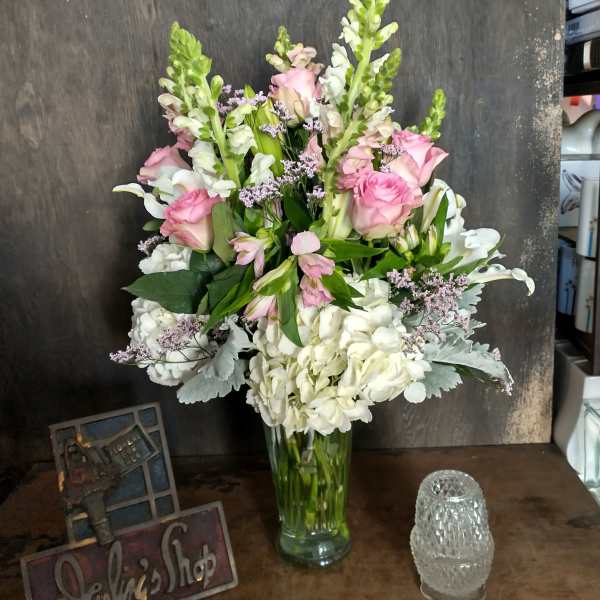 Pink roses and white flowers arranged in a clear glass vase