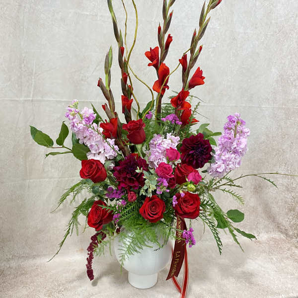 Tall red and pink floral arrangement in a white vase