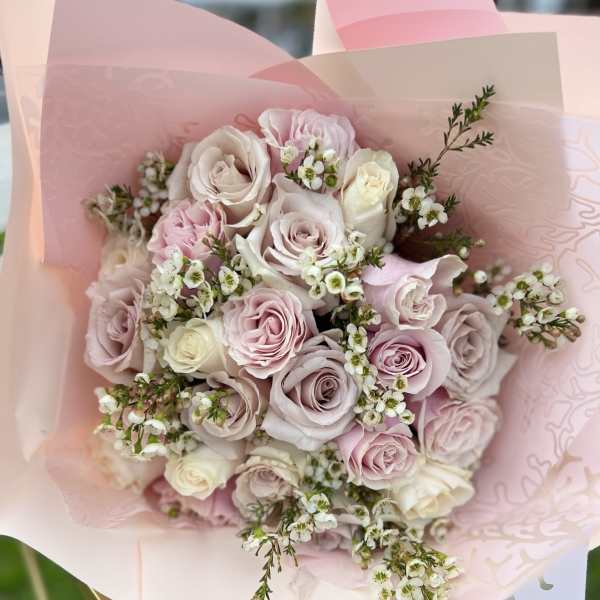 Bouquet of pale pink and white roses wrapped in pink paper