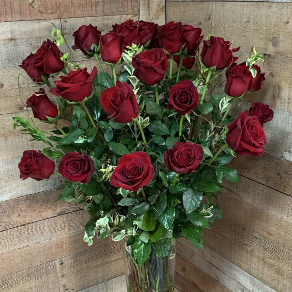 Tall vase arrangement of red roses with greenery