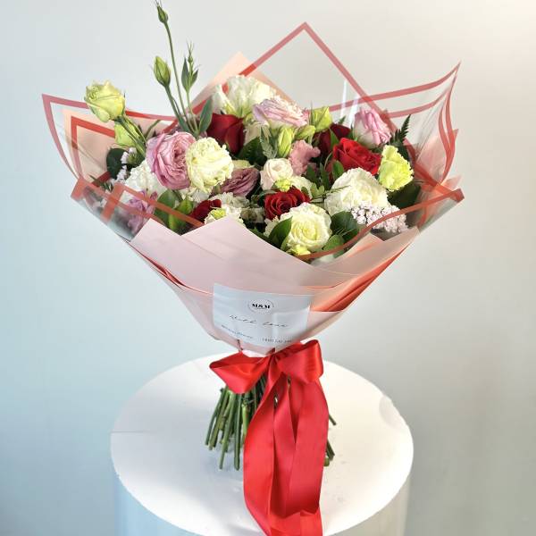 Bouquet of pink, red, and white roses wrapped in pink paper with a red ribbon