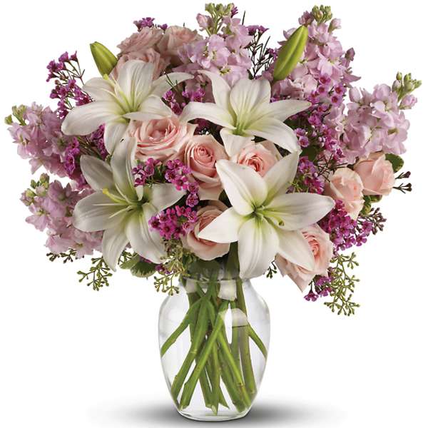 Pink roses and white lilies arranged in a clear glass vase