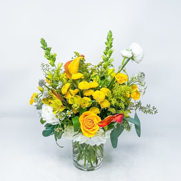 Yellow and white mixed flower arrangement in a clear glass vase
