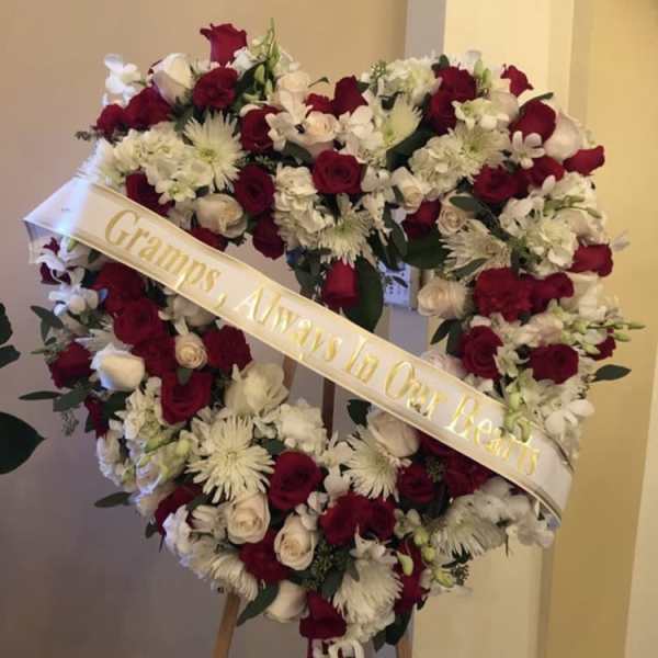 Heart-shaped floral wreath with red and white flowers on an easel