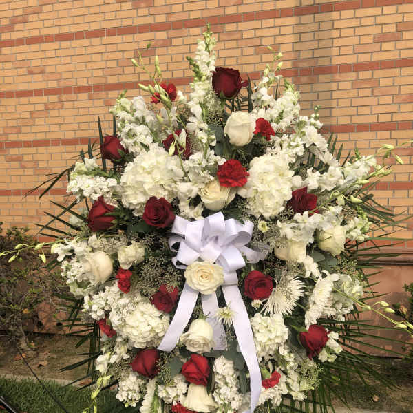 Large standing floral spray with red and white roses and a white ribbon bow