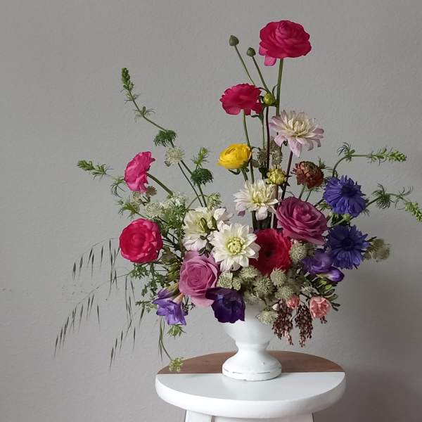 Mixed bouquet of colorful flowers in a white pedestal vase